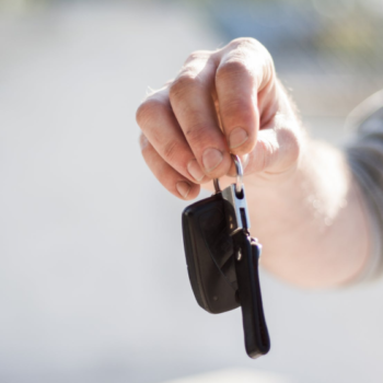 A man hands over some keys to a new car buyer