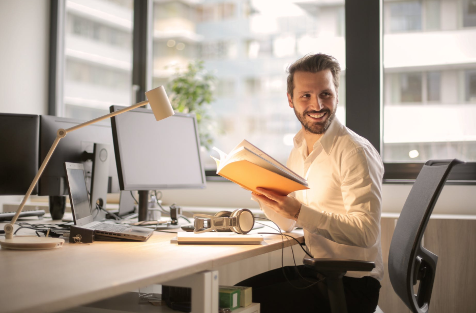 A man smiles at his desk and looks full of energy in the work place