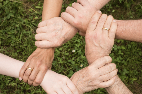 A group of hands interlock featuring people from mixed generations